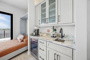 A modern kitchen with white cabinets, a marble countertop, and a built-in dishwasher. - Waterfront Fun, Private Beach, Pool, Spa & Games - Laguna Lake House - Roelens (Cape Coral)