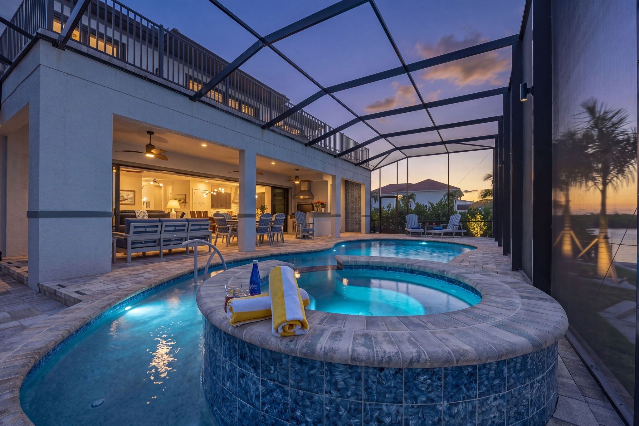 Ein moderner Poolbereich im Freien mit einer überdachten Terrasse, Sitzgelegenheiten und Blick auf die Landschaft.