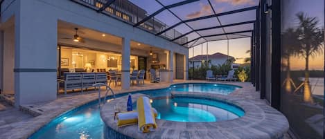 A modern outdoor pool area with a covered patio, seating, and a view of the landscape.
