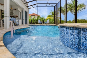 Ein Schwimmbecken mit einer gefliesten Kante, Liegestühlen und einem überdachten Bereich mit Deckenventilator.