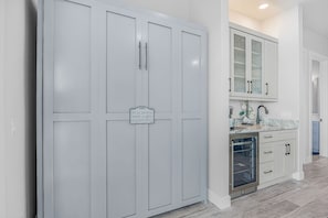 A kitchen with white cabinets, a stainless steel refrigerator, and a pull-down hide-a-bed feature. - Waterfront Fun, Private Beach, Pool, Spa & Games - Laguna Lake House - Roelens (Cape Coral)