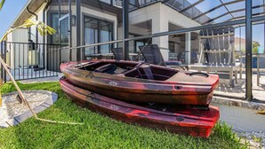 A boat parked on a grassy area with a modern building in the background. - Waterfront Fun, Private Beach, Pool, Spa & Games - Laguna Lake House - Roelens (Cape Coral)