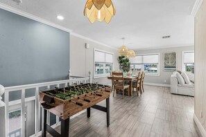 A spacious room with a foosball table, a dining area with a table and chairs, and a sofa. - Gulfside Fun, Pool Days & Waterfront Adventures Await - Coastal Oasis - Roelens (Fort Myers Beach)