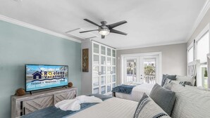 Ein Hotelzimmer mit einem Bett, einem Fernseher, der eine Urlaubsanzeige zeigt, einem Deckenventilator und Blick ins Freie.