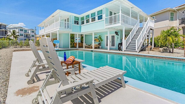 Ein Poolbereich mit Liegestühlen, einem kleinen Tisch und einer Treppe, die zu einer zweiten Etage führt.