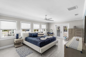 A bedroom with a bed, bedside tables, a ceiling fan, and a view of the outside. - Gulfside Fun, Pool Days & Waterfront Adventures Await - Coastal Oasis - Roelens (Fort Myers Beach)