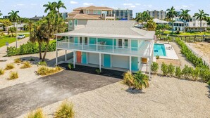 Ein Strandgrundstück mit zwei Etagen, das einen Swimmingpool, eine überdachte Terrasse und Meerblick bietet.