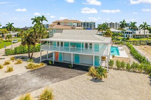 A two-story beachfront property with a swimming pool, a covered patio, and a view of the ocean. - Gulfside Fun, Pool Days & Waterfront Adventures Await - Coastal Oasis - Roelens (Fort Myers Beach)