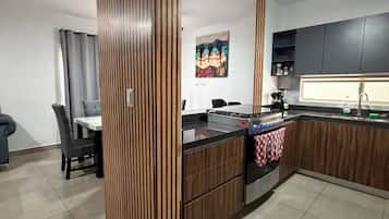 Une cuisine moderne dotée d’un îlot central, de meubles de couleur sombre et d’un ventilateur de plafond.