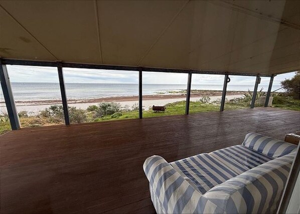 A covered outdoor seating area with a view of the beach and ocean.