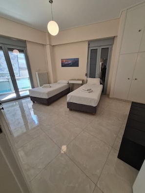 A modern hotel room with two beds, a small table, and a large window. -  Acropolis Museum Grand Mansion (Athina)