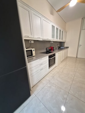 A kitchen with white cabinets, a microwave, a toaster, and a sink. -  Acropolis Museum Grand Mansion (Athina)