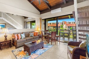 Un vaste espace de vie comprenant un canapé, des fauteuils, une table à manger et un balcon offrant une vue sur les bâtiments.