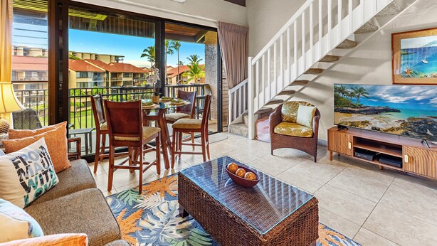 Een hotelkamer met balkon, eethoek, bank, televisie en een trap.
