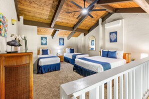 Une chambre avec deux lits, un ventilateur de plafond et des œuvres d’art accrochées aux murs.