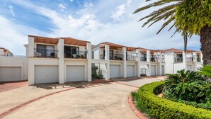 A multi-story residential building with balconies, garage doors, and a landscaped garden. - Breakers 5/5- Stone Real Estate Yamba (Yamba)
