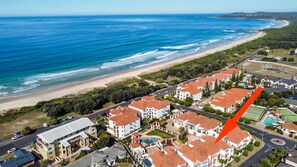 An aerial view of a coastal residential area with beachfront properties, a road, and a swimming pool. - Breakers 5/5- Stone Real Estate Yamba (Yamba)
