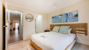 A bedroom with a bed, a wooden headboard, a painting, and a mirror on the wall. - Breakers 5/5- Stone Real Estate Yamba (Yamba)