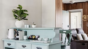 Una cocina con un armario azul claro, una cafetera, un hervidor y una planta en maceta.