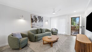 Ein modernes Wohnzimmer mit einer grünen Sofagarnitur, einem runden Couchtisch und einem grauen Sessel.
