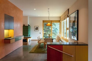 A modern kitchen with a dining area, large windows, and a view of trees. - The Gallery House | Architectural Digest–Featured Ketchum Home (Ketchum)