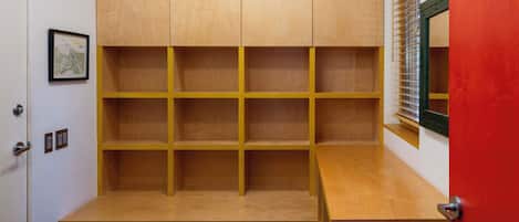 Ein Zimmer mit einer eingebauten Holzwandregal, einem kleinen Schreibtisch und einer roten Tür.