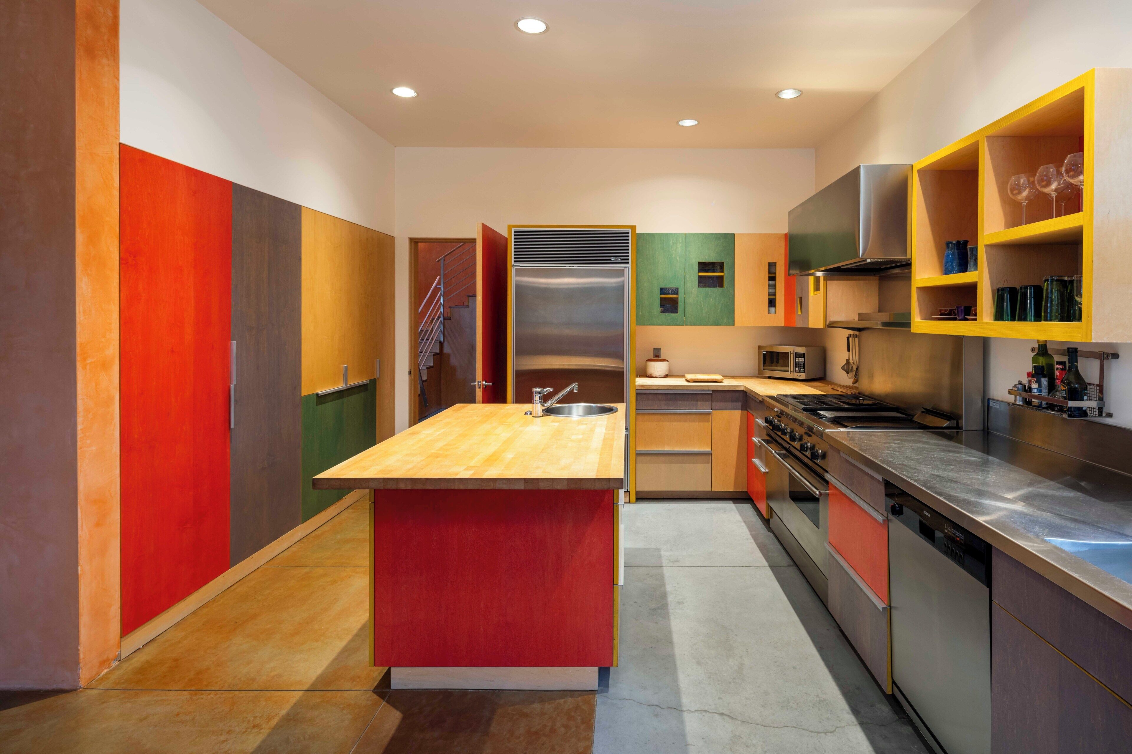 A modern kitchen with a central island, stainless steel appliances, and a variety of cabinets.