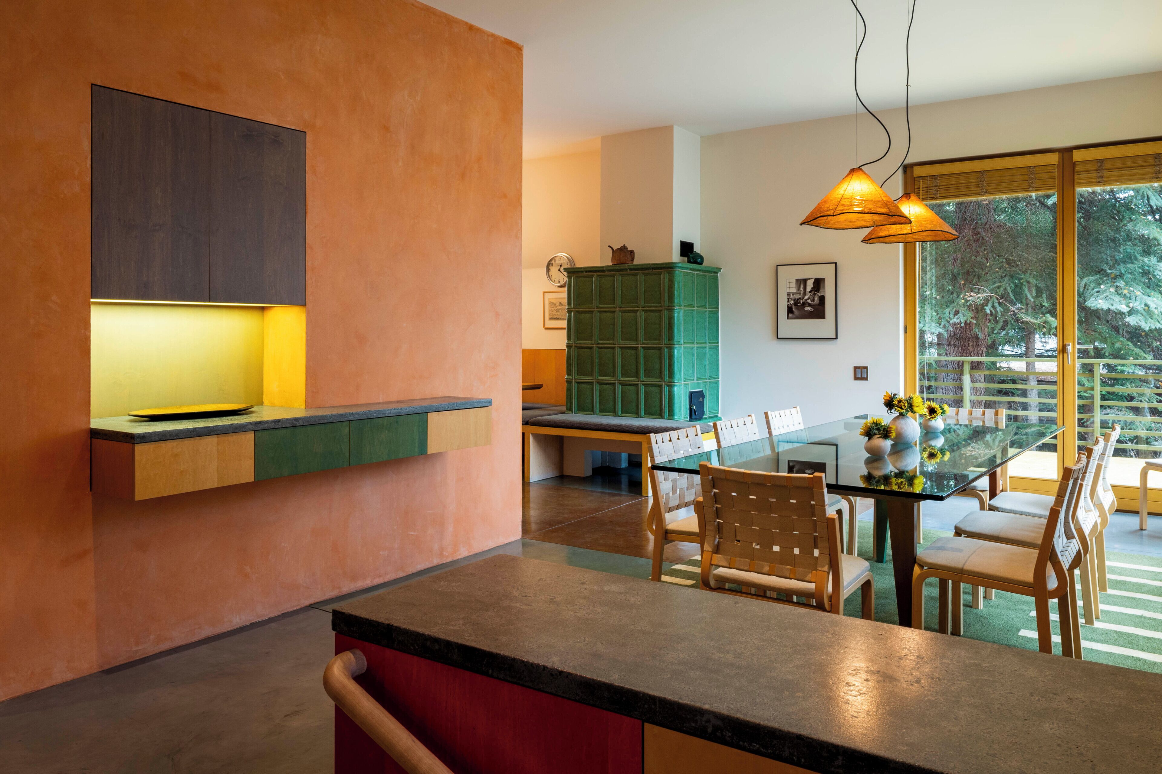 Una cocina moderna con isla integrada, un comedor con mesa de vidrio y vistas al exterior.