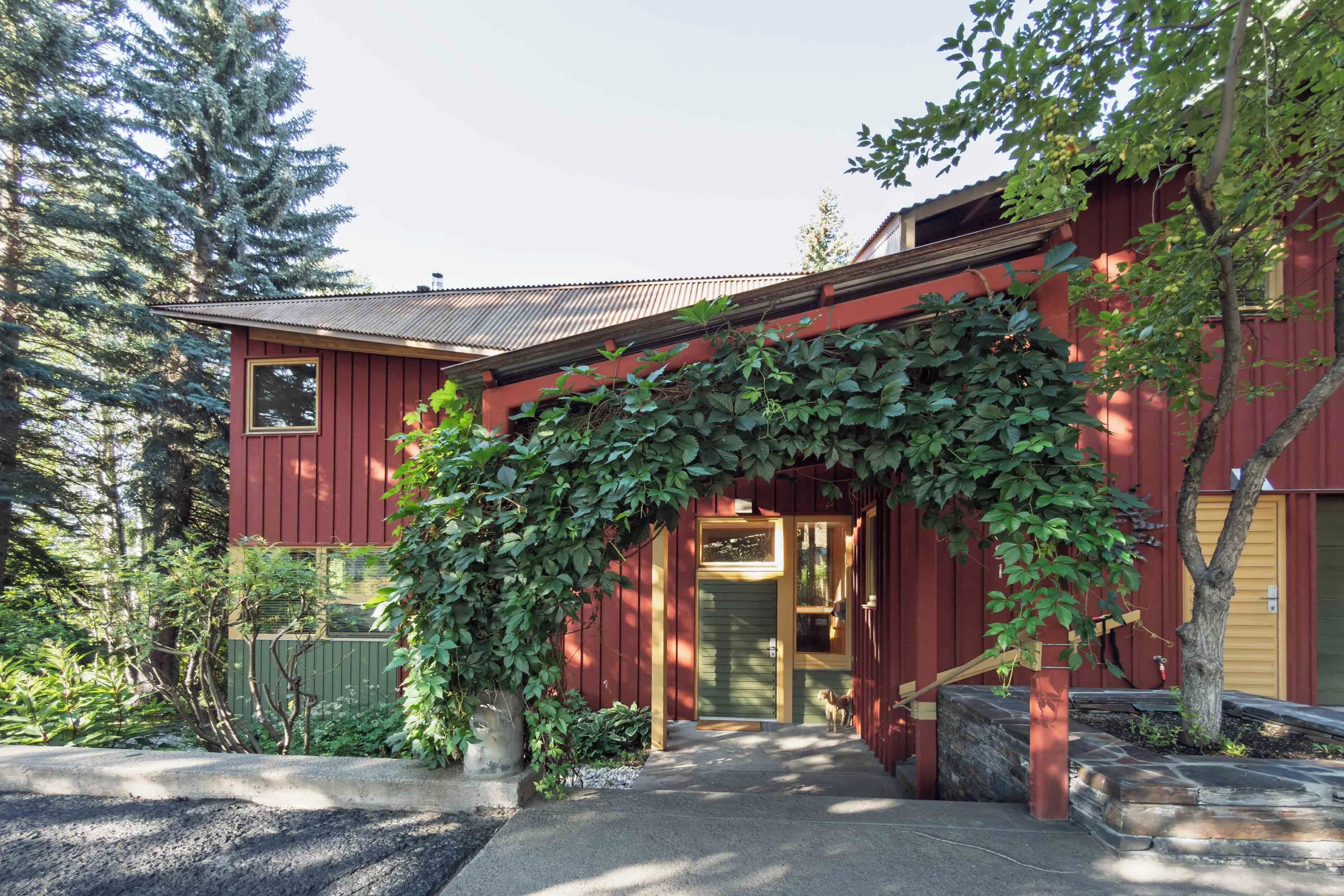 A red wooden house with a green door and a covered entrance.