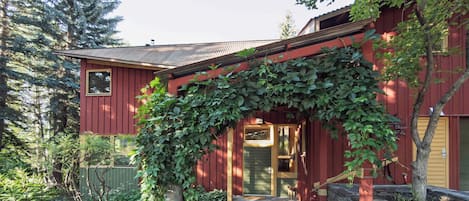 Una casa de madera roja con una puerta verde y un porche cubierto.