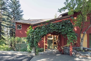 A red wooden house with a green door and a covered entrance. - The Gallery House | Architectural Digest–Featured Ketchum Home (Ketchum)
