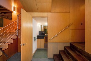 A wooden interior with a staircase, a kitchen area, and a bathroom. - The Gallery House | Architectural Digest–Featured Ketchum Home (Ketchum)