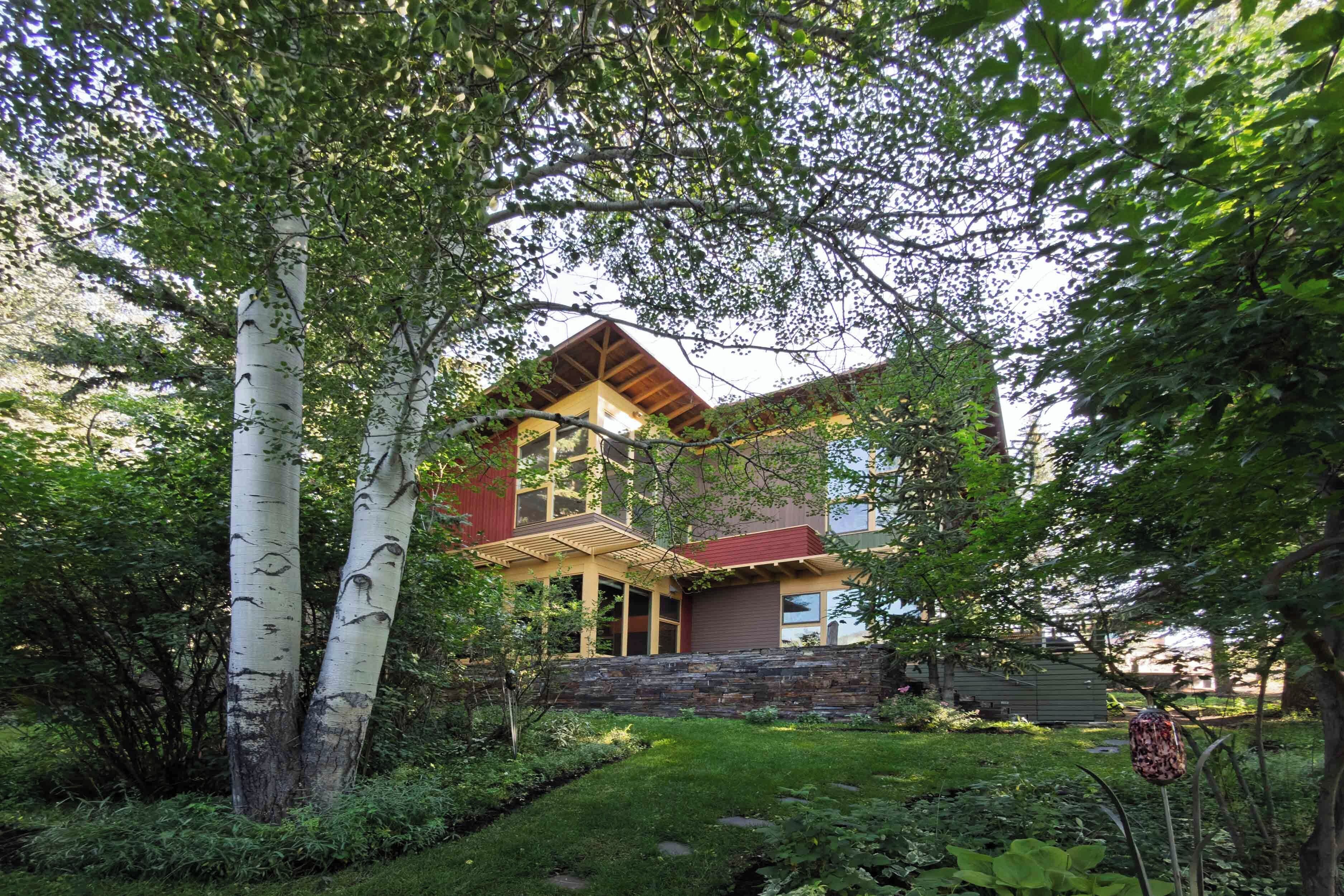 A two-story house with a stone foundation, large windows, and a wooden deck.