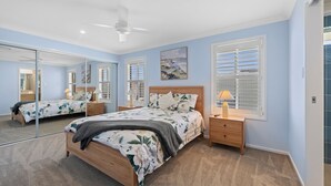 A bedroom with a bed, bedside tables, a ceiling fan, and a large mirror. - Yamba Waters - Pet Friendly Waterfront Escape with Private Jetty (Yamba)