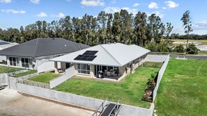 A residential property with a covered patio, solar panels, and a well-maintained lawn. - Yamba Waters - Pet Friendly Waterfront Escape with Private Jetty (Yamba)