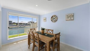 A dining area with a view of a body of water and houses. - Yamba Waters - Pet Friendly Waterfront Escape with Private Jetty (Yamba)