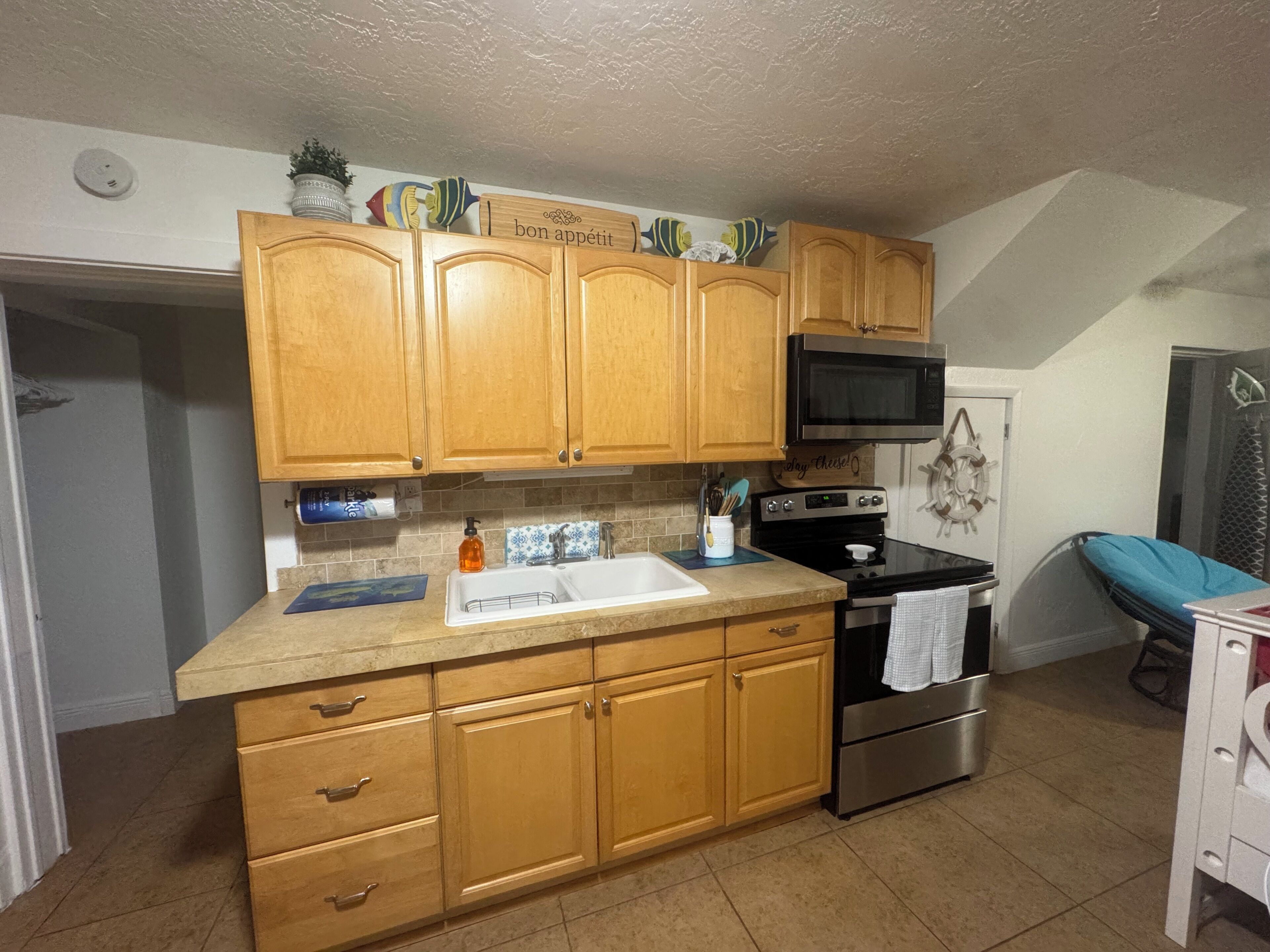 A kitchen with wooden cabinets, a stainless steel sink, a microwave, and a stove.