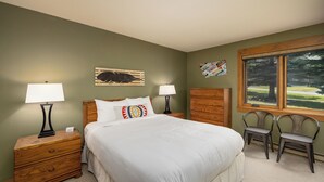 Un dormitorio con cama, dos mesitas de noche, cómoda y ventana con vistas, además de una pared con una placa de matrícula.