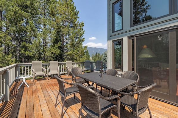 A wooden deck with outdoor furniture, including a table and chairs, and a glass door leading to the interior.