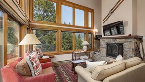 Una sala de estar acogedora con chimenea, ventanas amplias y una zona de estar confortable.