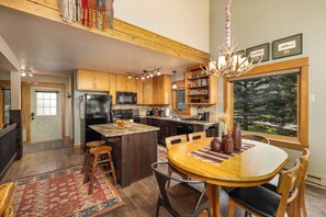 A spacious kitchen with wooden cabinets, a central island, and a dining area with a large window.