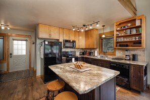 Eine moderne Küche mit Granit-Arbeitsplatten, Holzschränken, einem Einbauofen, einer Mikrowelle und einer Kaffeemaschine.