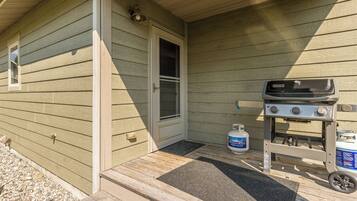 A wooden exterior with a gas grill and propane tank on the porch.