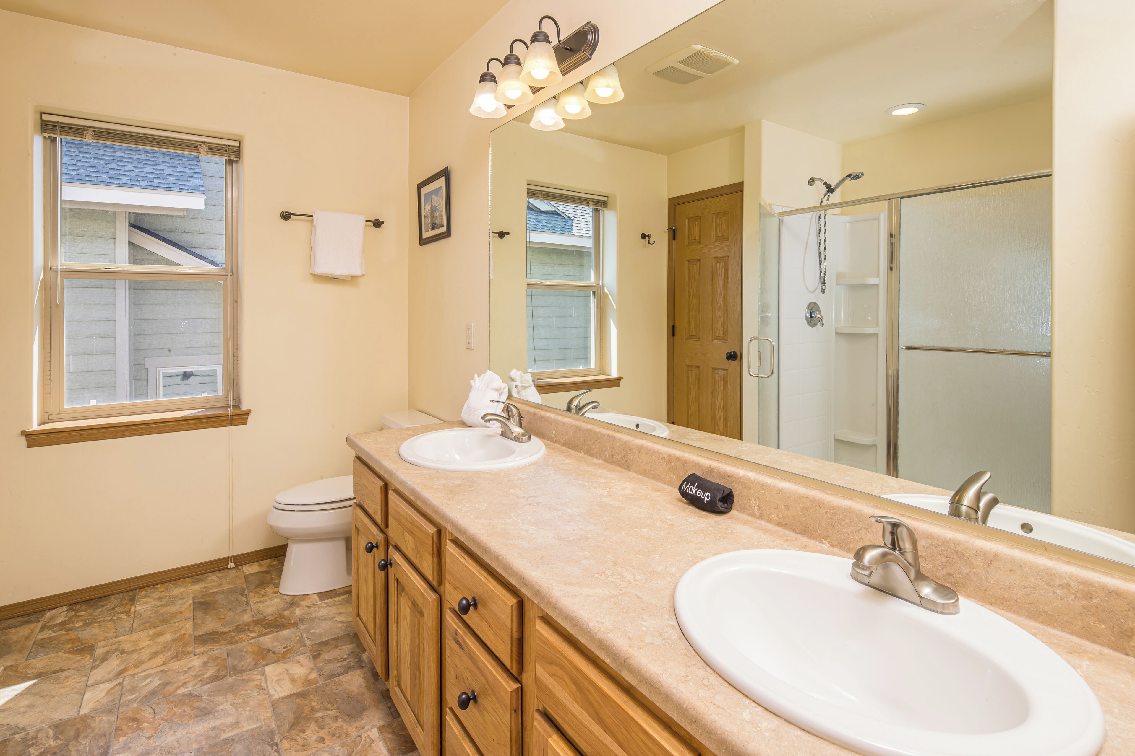 A bathroom with two sinks, a toilet, a shower, and a large mirror.