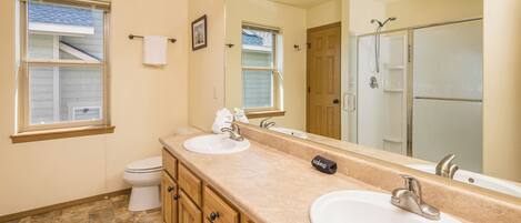 A bathroom with two sinks, a toilet, a shower, and a large mirror.