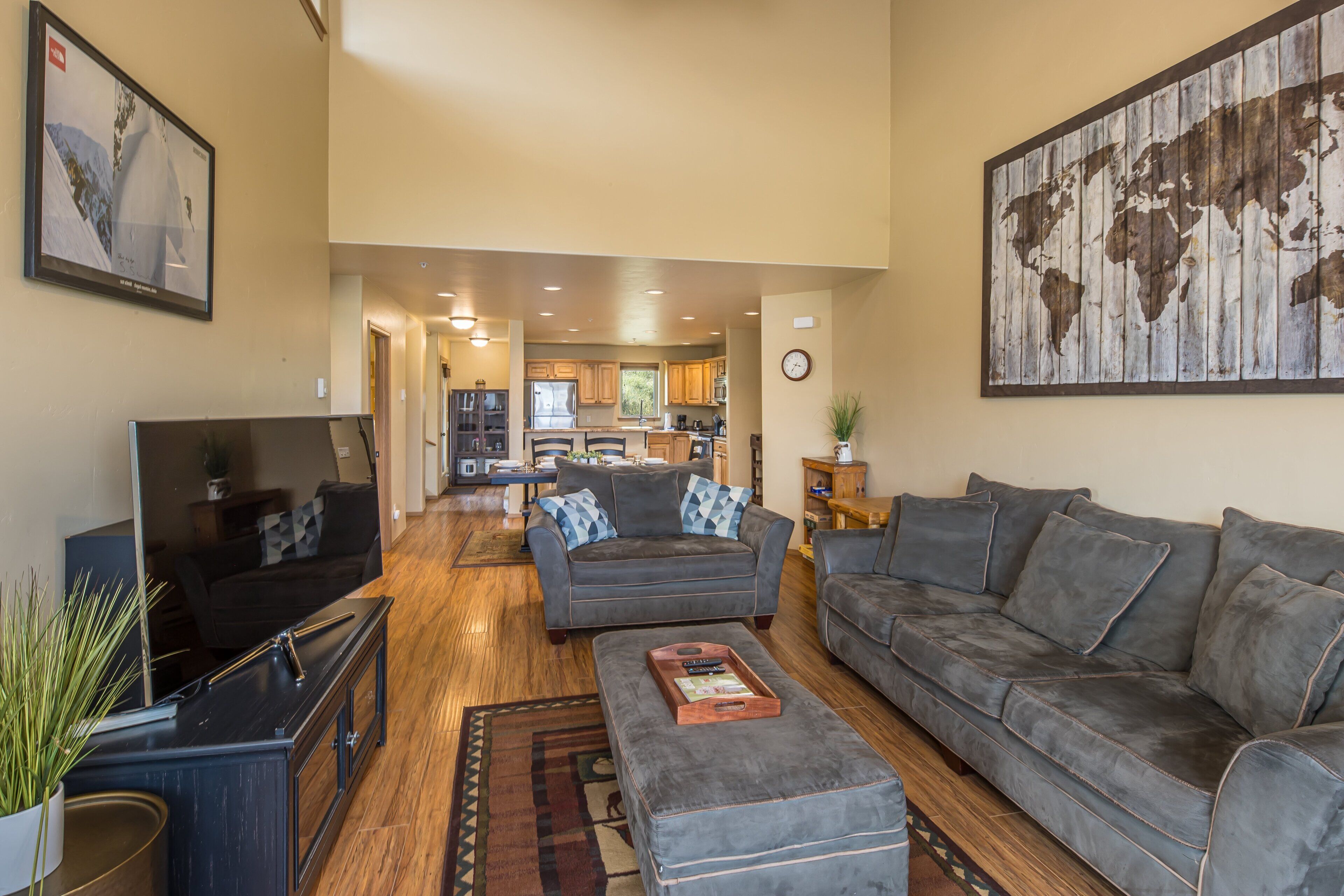 A spacious living room with a large grey sofa, a television, and a coffee table.
