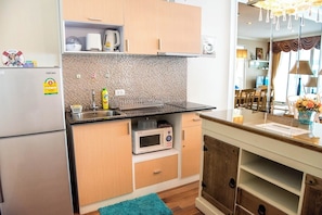 Eine kompakte Küche mit Mikrowelle, Kaffeemaschine und kleinem Kühlschrank.