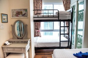 Una camera con un letto a castello, una cassettiera, uno specchio e una finestra con tende.