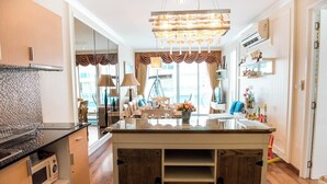 A modern kitchen with a central island, wooden cabinetry, and a large window with curtains. - D606 Bright 2-bedroom apartment with Playground near Sea, city (Huahin)