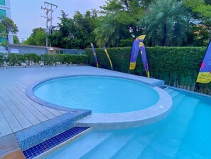 Ein runder Pool mit Fliesenrand, umgeben von einer Holzterrasse.